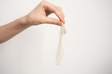 The hand holds a used condom
