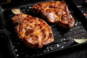 Grilled pork steak in a frying pan. 
