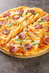 Freshly cooked hot pizza with french fries, sausages, cheese, tomato sauce close-up on a wooden board on the table. Vertical