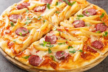 Americana Pizza with french fries, wurstel sausages, mozzarella cheese, tomato sauce and herbs close-up on a wooden board on the table. Horizontal