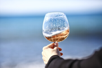 a glass of port wine on the background of the sea, a hand with wine