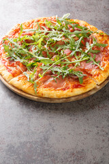 Prosciutto Pizza with cheese, tomato sauce and fresh arugula close-up on a wooden board on the table. Vertical