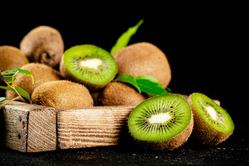 Ripe kiwi with leaves on a wooden tray. 