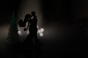 Black silhouettes of pair dancers performing. Man and woman are dancing on gray background with...