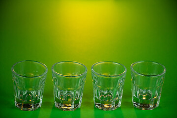 Empty shot glasses lined up against emerald green theme background waiting to be filled and slammed...