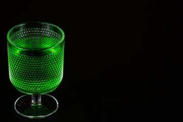 glass filled with emerald green spirit cocktail with black background to be drunk at celebrations for St Patrick's day. Irish holiday is popular drinking event when people party and drink excessively