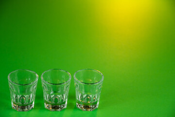 Empty shot glasses lined up against emerald green theme background waiting to be filled and slammed in celebrations for St Patrick's day. Irish holiday is popular drinking event when people party