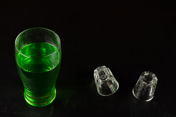 glass filled with emerald green spirit cocktail with black background to be drunk at celebrations...