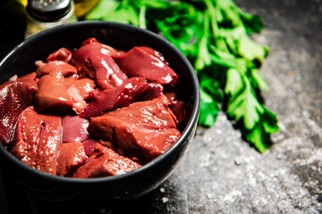 Sliced raw liver in a bowl with parsley.