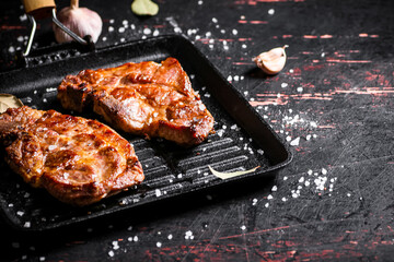 Grilled pork steak in a frying pan. 