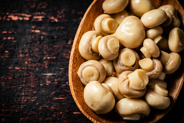 Pickled mushrooms in a wooden plate on the table. 