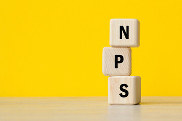 concept word NPS. Net Promoter Score. wooden cubes. TEXT. YELLOW BACKGROUND. Business concept. Copy space