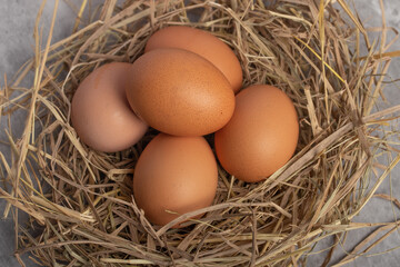 Fresh chicken eggs in straw, gray background. Copy space.