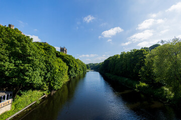 Fototapeta na wymiar Durham England: 2022-06-07: Durham Cathedral on the River Wear during sunny summer day with lush green trees and blue sky