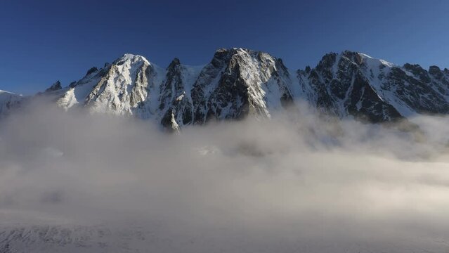 Snowy mountains timelapse Les Drus with Argentiere glacier covered by clouds at the bottom with clear skies during the morning in spring in the French Alps, Chamonix, France