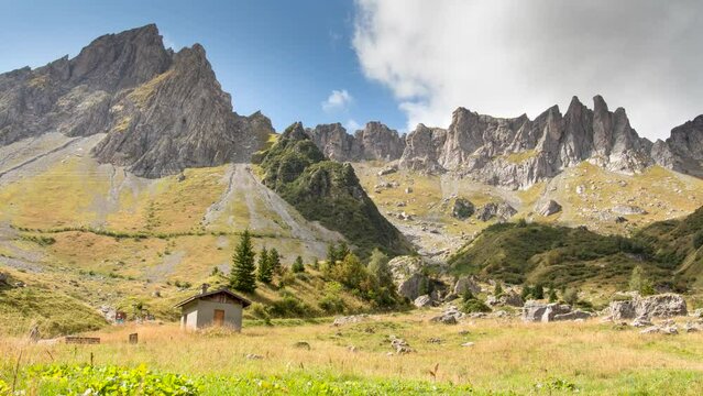 Alpine Rocky mountains with small house timelapse during cloudy day in summer in Tour du Mont Blanc hike in France near refuge des Mottets
