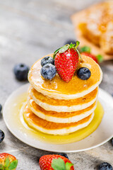 Pancakes with honey and berries on a plate.