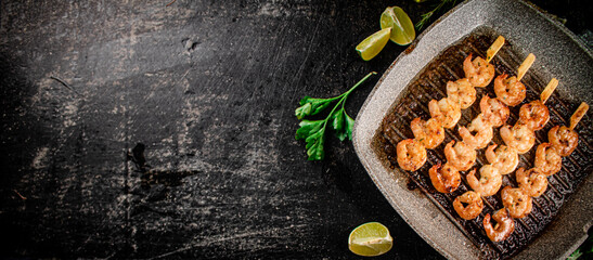 Grilled shrimp in a frying pan with parsley and pieces of lime. 