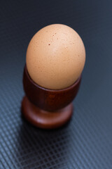 a boiled egg placed in a  wooden brown  support