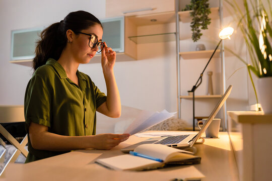 Caucasian young wearing glasses woman working at laptop. Student learning in home. Side view. Concept of remote work and freelancing