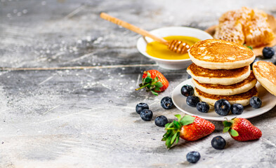 Pancakes in a plate with berries and honey. 