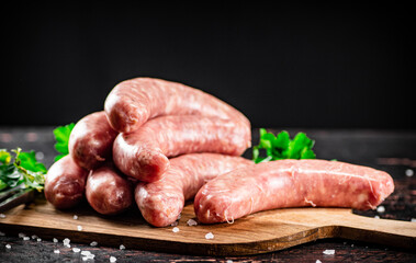 Raw sausages on a cutting board with parsley. 