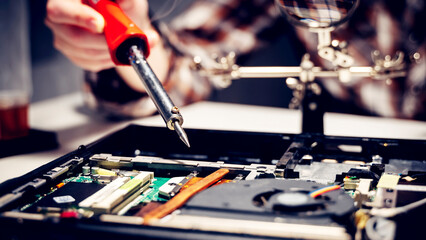 a computer master solders a chip and a board on a laptop, the concept of electronics repair shops