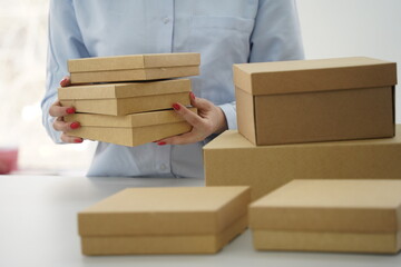 A woman holds cardboard boxes for parcels and delivery