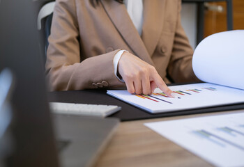 Business woman working at office  graph data documents on her desk.Young business woman sitting at the desk analyzing documents working on company project in office.