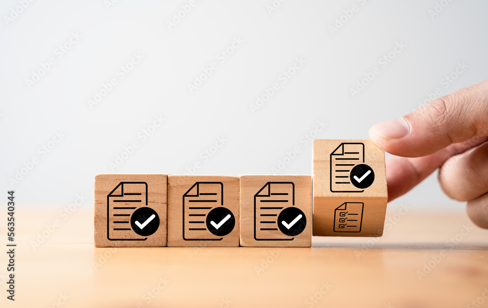 Poster Hand Flipping correct sign with document which print screen on wooden cube block for prepare check and approve document , Quality assurance and ISO guarantee concept.