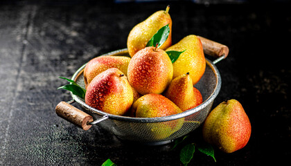 Fototapeta na wymiar Juicy pears in a colander with foliage.