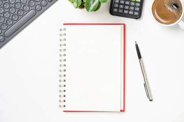 Top view of blank notebook with pen coffee calculator and computer keyboard for office working desk concept.