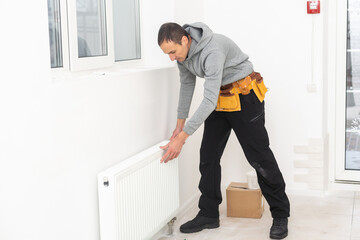Man is repairing radiator battery in the room. Maintenance repair works renovation in the flat. Heating restoration