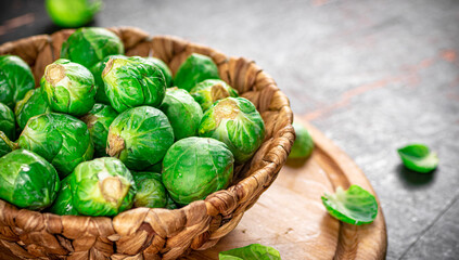 Brussel cabbage in a basket on a cutting board.