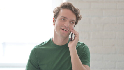 Young Man Talking on Phone, Discussing Work