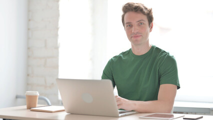 Smiling Man Shaking Head in Acceptance while Working on Laptop