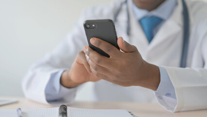 Close Up of African Doctor Browsing Internet on Smartphone