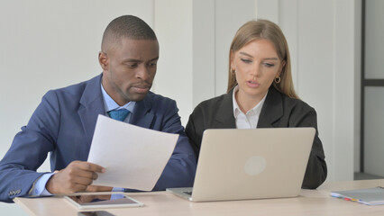 African Businessman and Businesswoman Discussing Work on Laptop