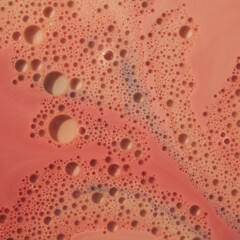 Large and small water balloons of different shapes painted from a bird's eye view on a pink background of an abstract whole