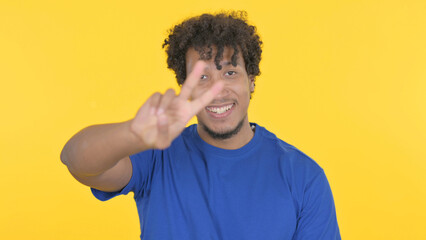 African Man with Victory Sign on Yellow Background
