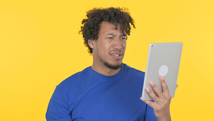African Man Reacting to Loss on Tablet on Yellow Background