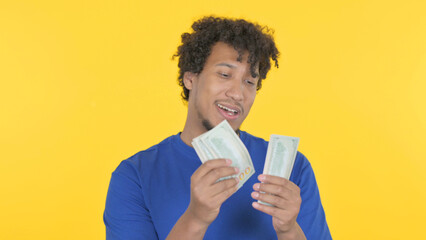 African Man Counting Dollars on Yellow Background