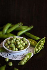 Green shoots of young peas, flowers and pods on a dark wooden background. selective focusing