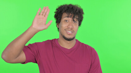 African Man Waving Hand to Say Hello on Green Background