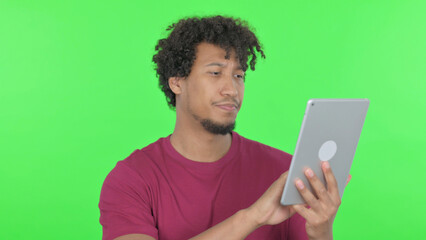 African Man using Digital Tablet on Green Background