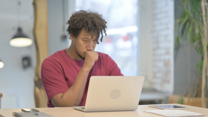 African Man Coughing while Working on Laptop