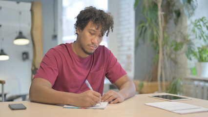 African Man Writing Letter in Office