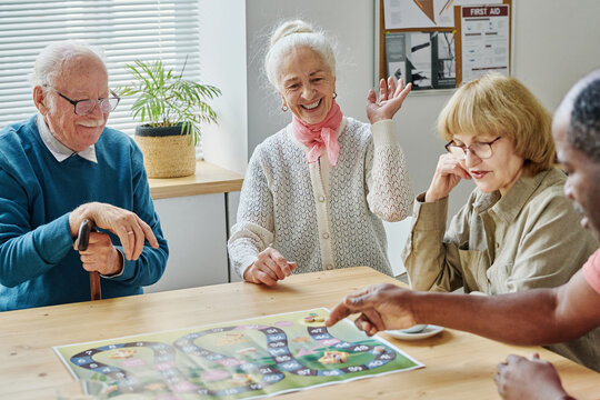 Group of senior people having fun playing board game together at table during leisure time