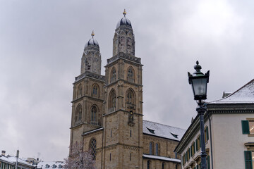 Fototapeta na wymiar Snow covered church tower of protestant church Great Minster at the medieval old town of Zürich on a snowy gray clouded alte autumn day. Photo taken December 16th, 2022, Zurich, Switzerland.