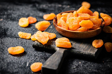 Dried apricots in a plate on a cutting board. 